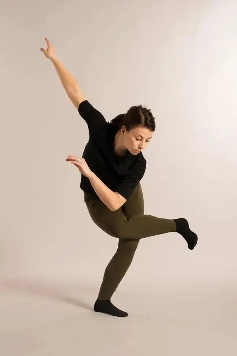 Sara i en dansebevegelse mot lys bakgrunn