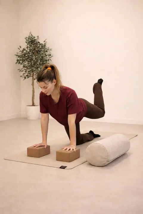 Sara på yogamatte med klosser og bolster i studioet